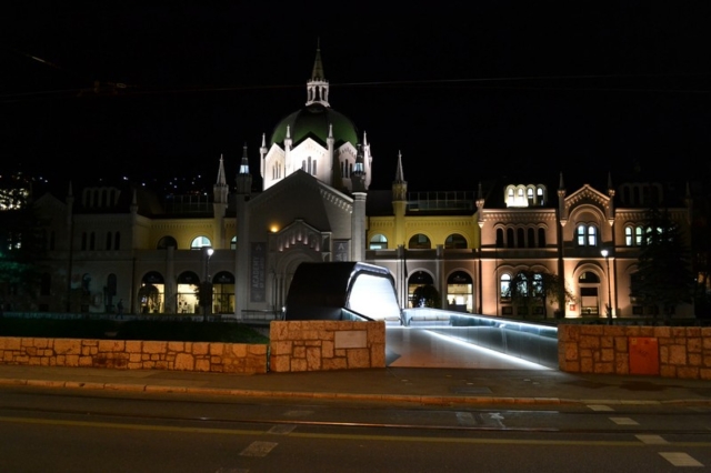 A bridge over the Miljacka river and the Academy of Fine Arts at night in Sarajevo